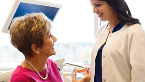 A Senior Lady Showing Her Dentures To a Denturist