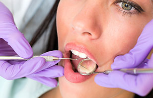 A female patient getting her teeth checked by a dentist