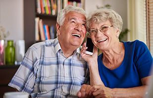 A Very Old Couple Smiling When Talking To Loved Ones Over Phone